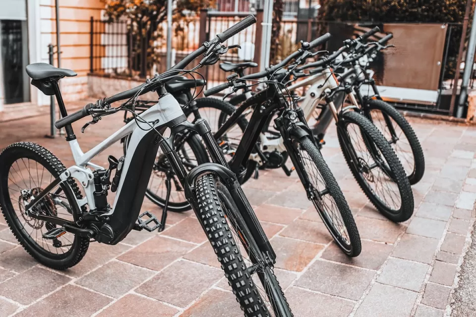 Black e-bikes sitting on a sidewalk outdoors.